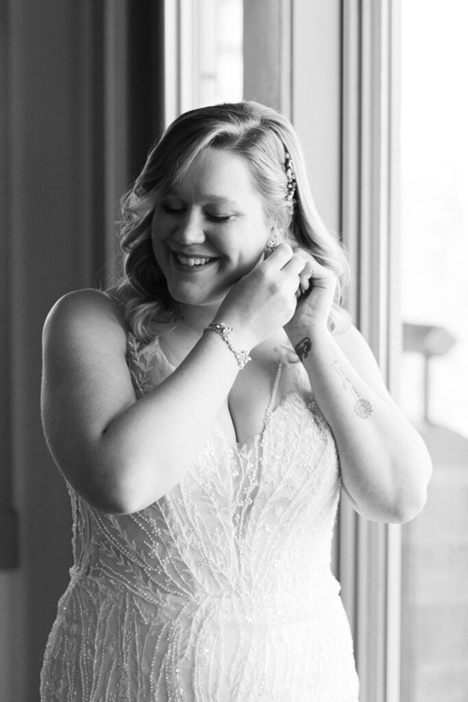 bride putting on earrings with window light at mountain top inn, chittenden, vt