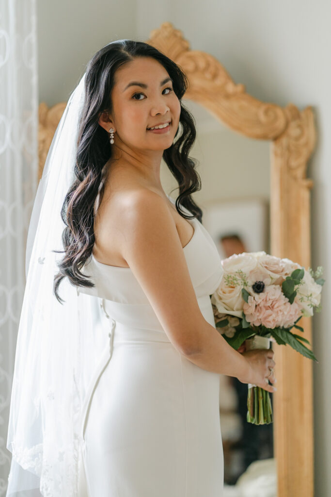 bride in her wedding dress standing in front of mirror
