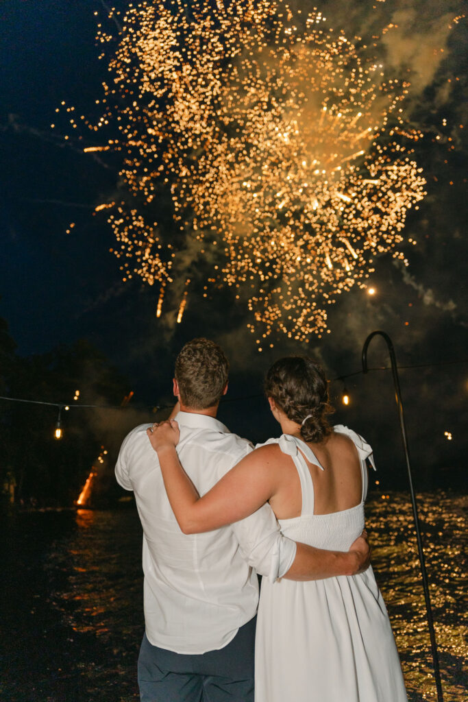 bride and groom watching fireworks from dock on wedding day