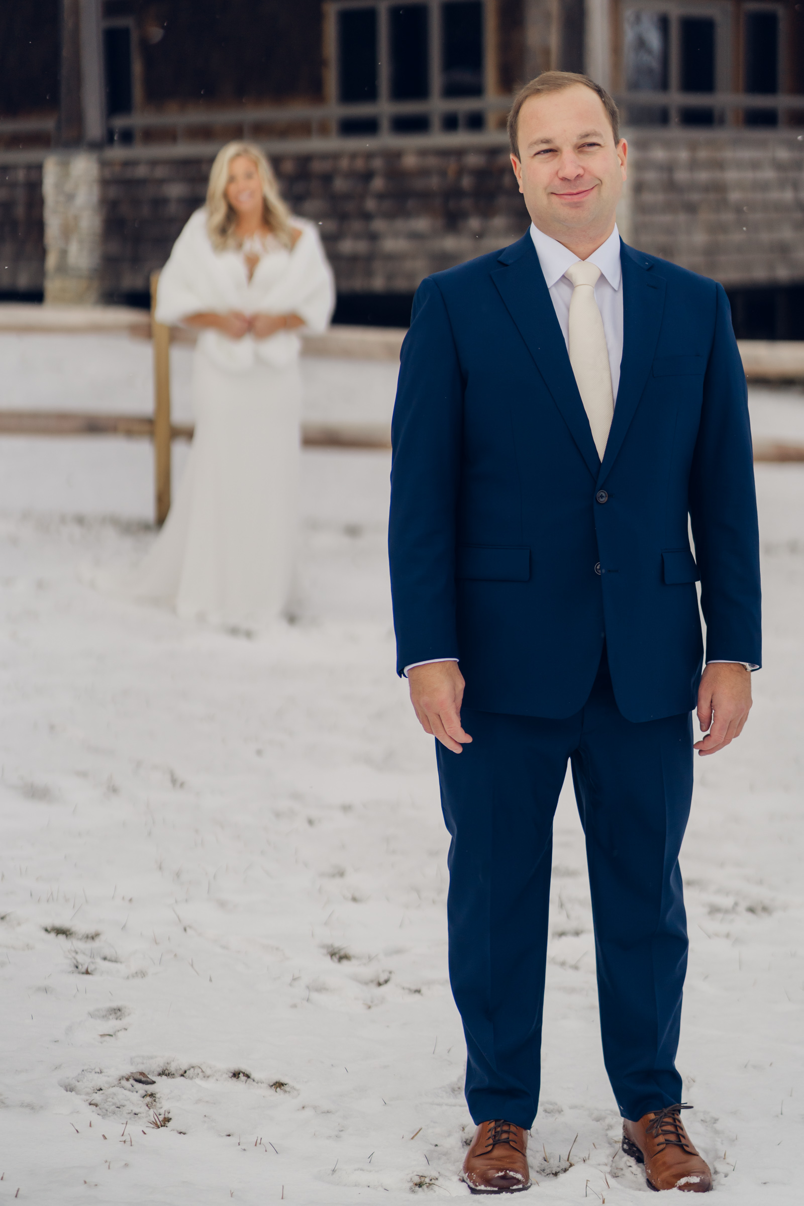 bride standing behind groom before first look during winter wedding at mountain top