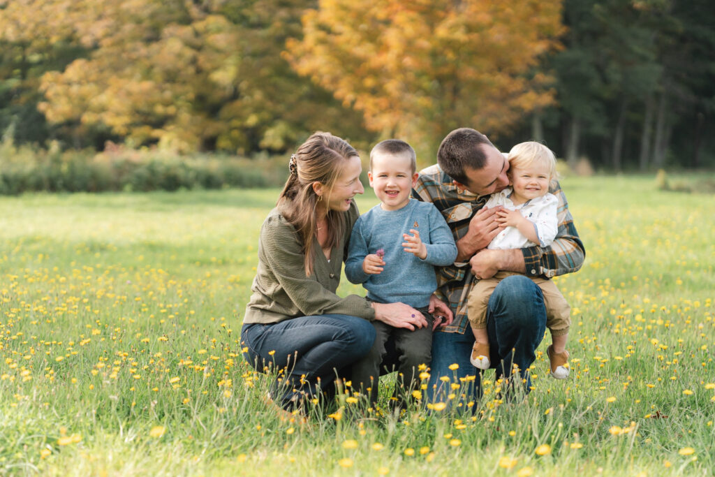 family kneeling in the grass during a fall photo session at Muster Field Farm