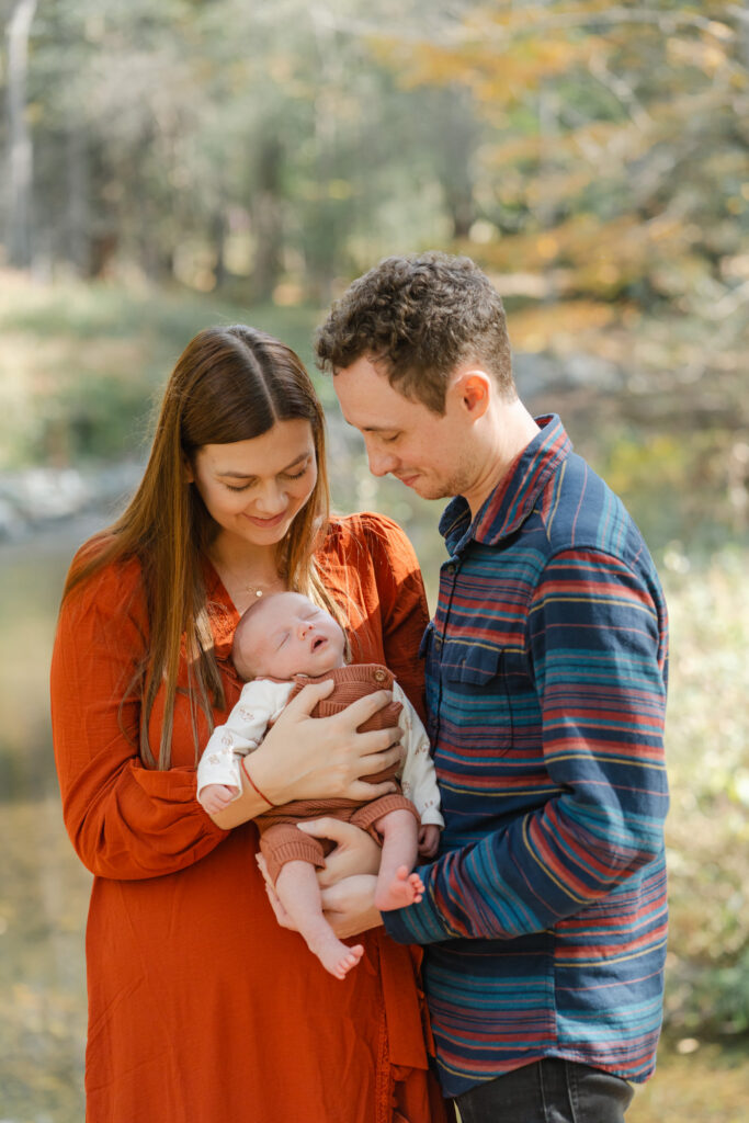 couple looking down at infant during photo session at Mink Brook in Hanover NH