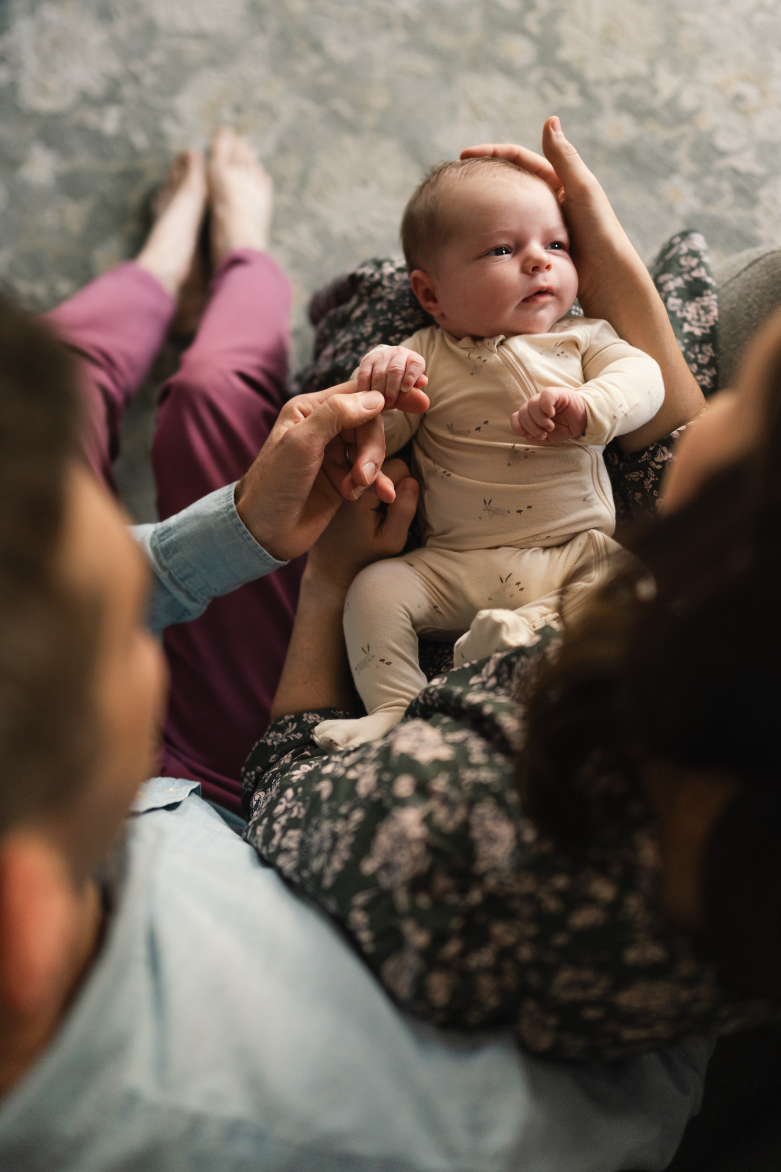 newborn baby on parents lap with soft light on side of face