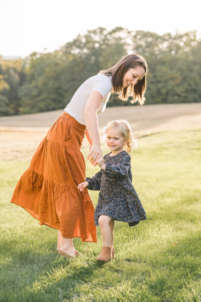 mother and daughter twirling in sunlight, during upper valley fall family photo session