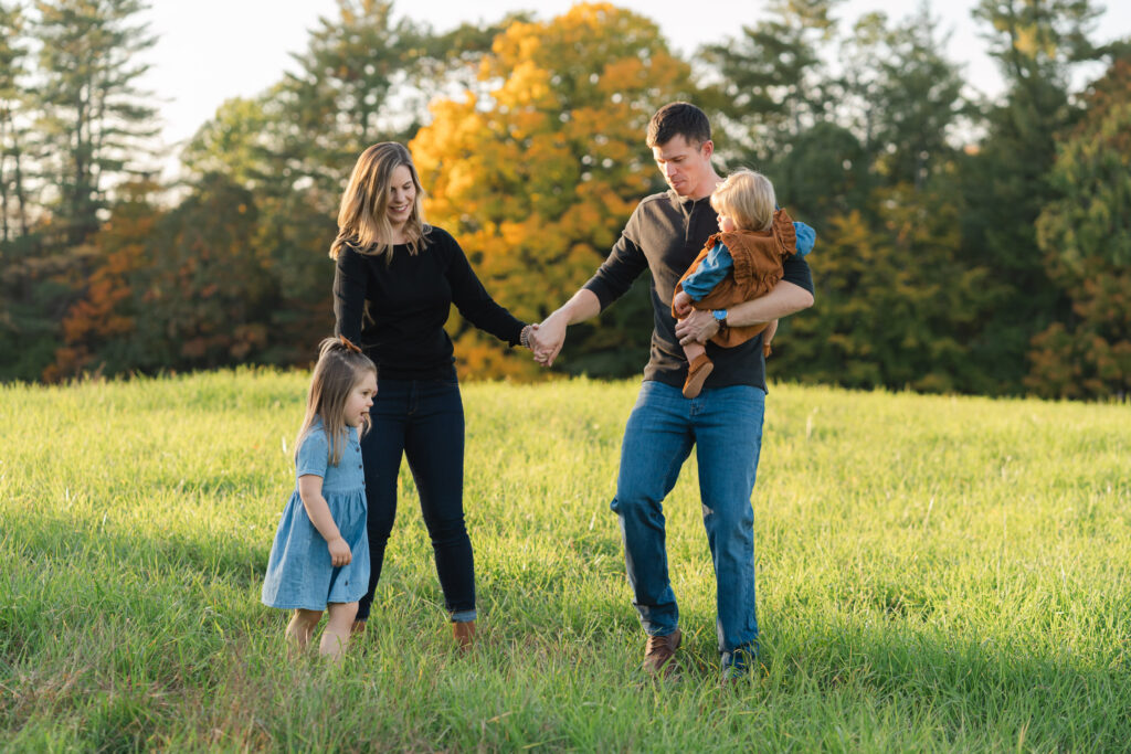 family walking in tall grass during photo session in the fall, new hampshire upper valley