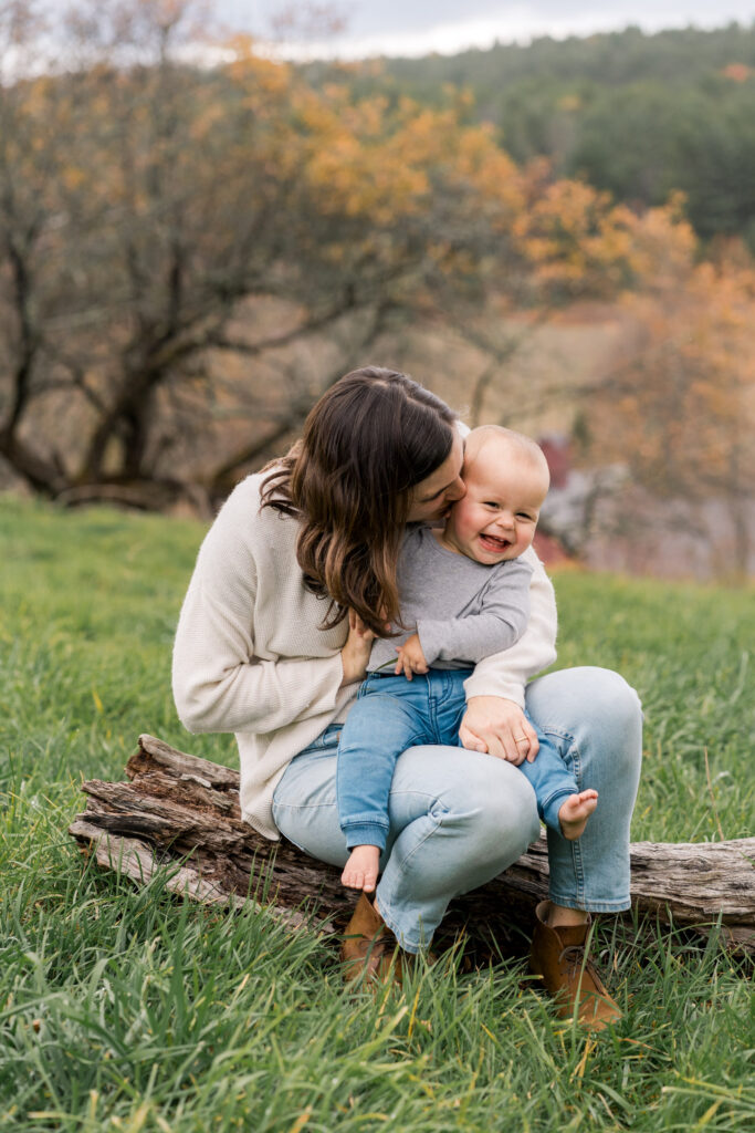 mother snuggling son while sitting on log during upper valley fall family photo session