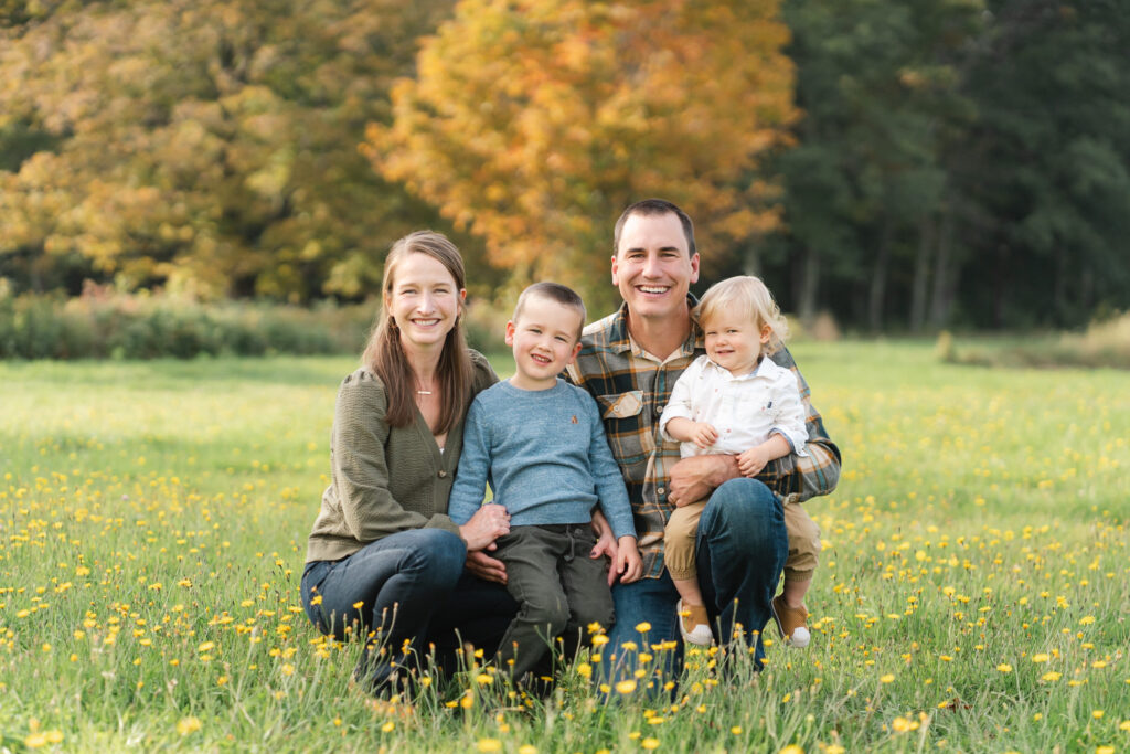 family kneeling in grass fall family photo session upper valley musterfield farm