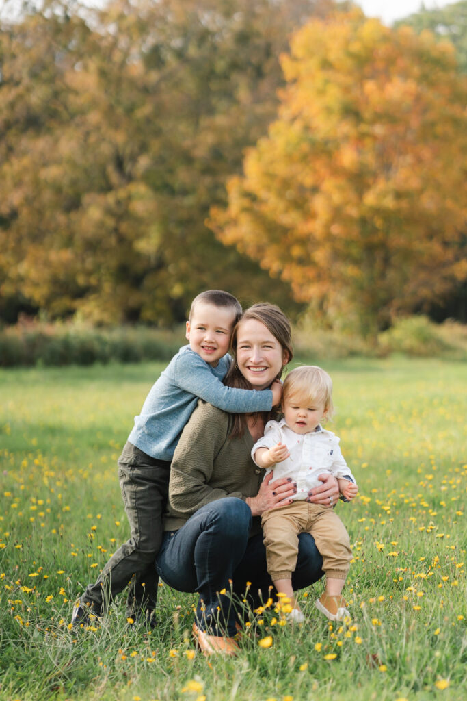 mother and boys crouching in field at fall photo session in the upper valley
