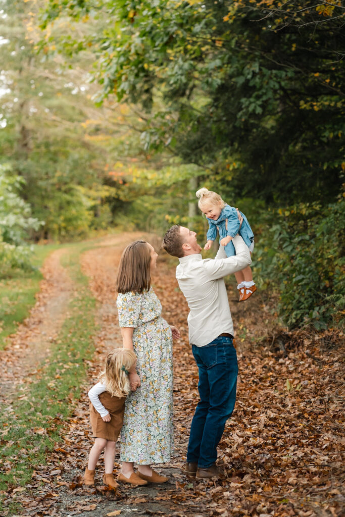 family of four on country path with leaves around them during upper valley fall family photo session