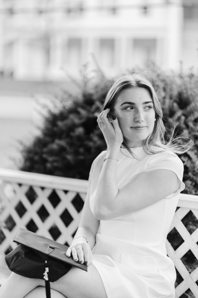 woman sitting in gazebo with grad cap brushing hair back
