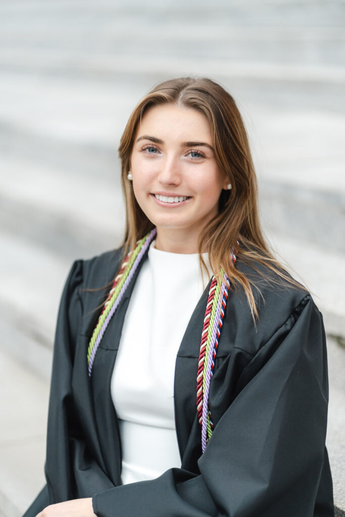 female grad sitting on steps of armory at norwich university during photo session