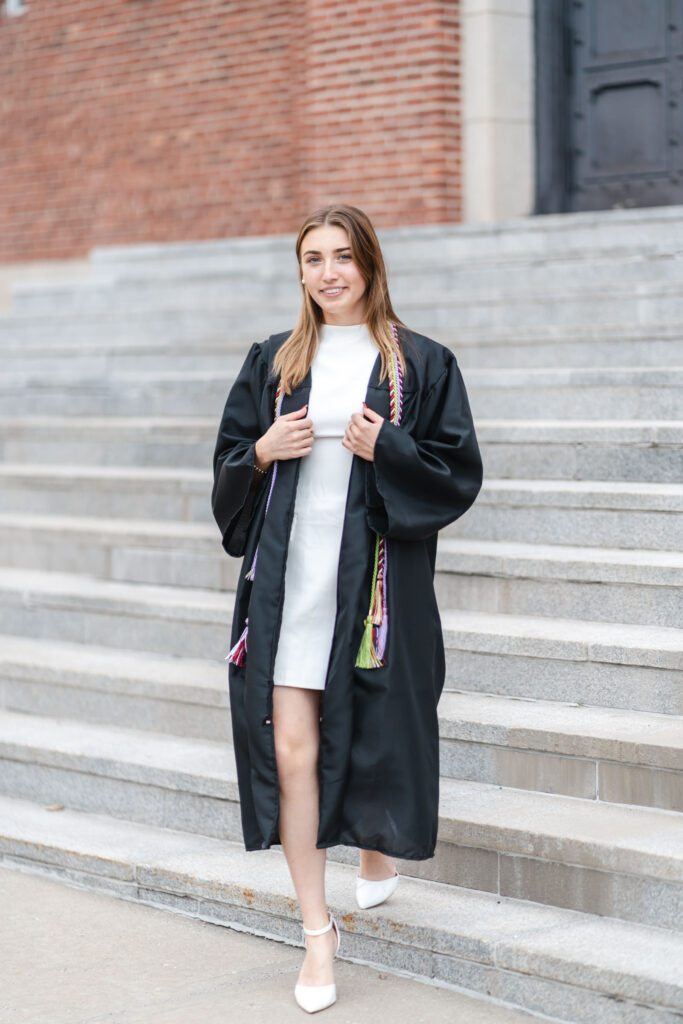 female grad walking down steps of armory at norwich university during photo session