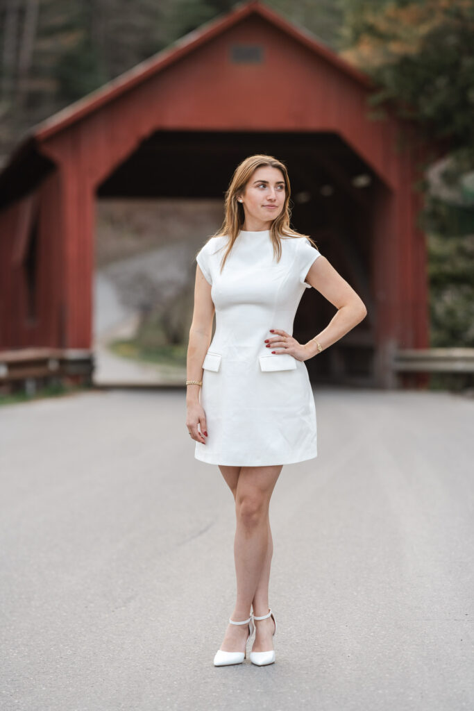 female in white dress posing in front of northfield vermont covered bridge