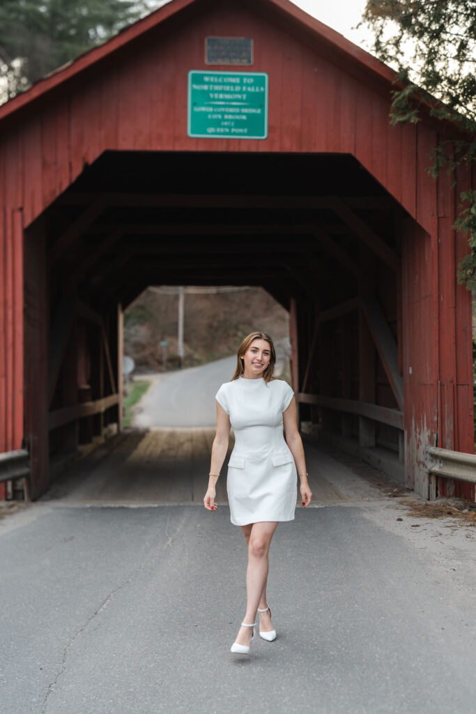 female in white dress walking away from northfield vermont covered bridge