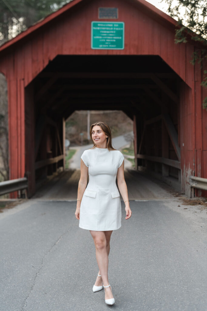 female in white dress walking away from northfield vermont covered bridge, not looking at camera