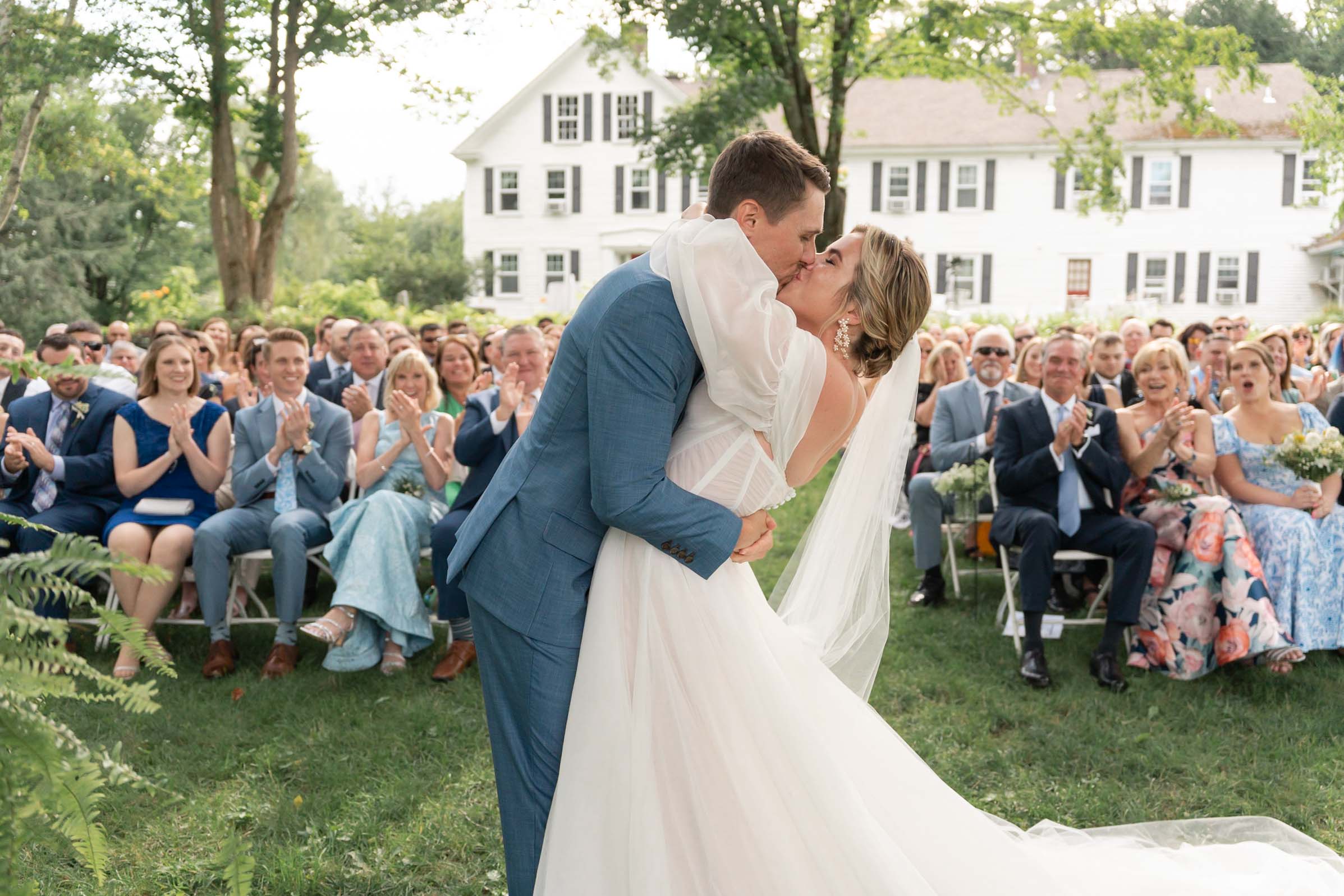 Quechee Vermont Wedding, Couple share first kiss with guests behind them