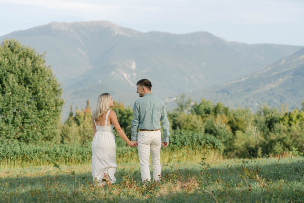 couple walking away toward mountains sugar hill white mountain engagement session