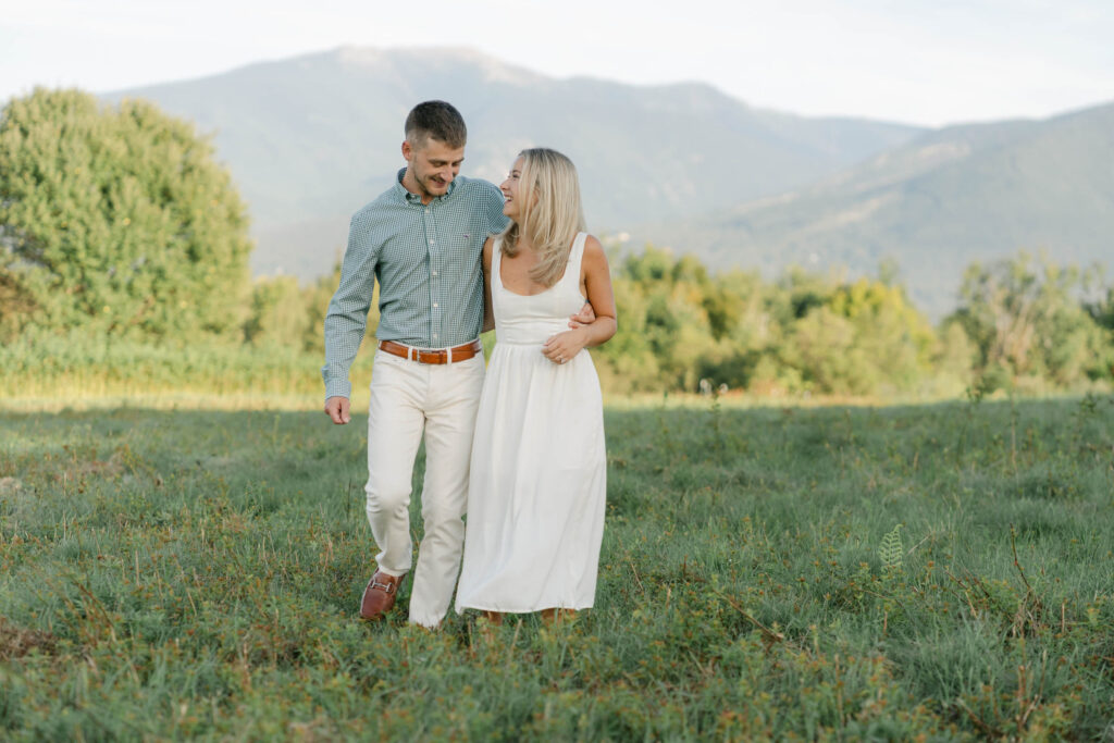 wide view of couple walking toward camera arm and arm during sugar hill white mountain engagement session