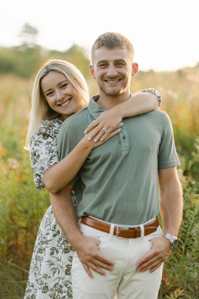 woman stands behind man wrapped arms around neck
