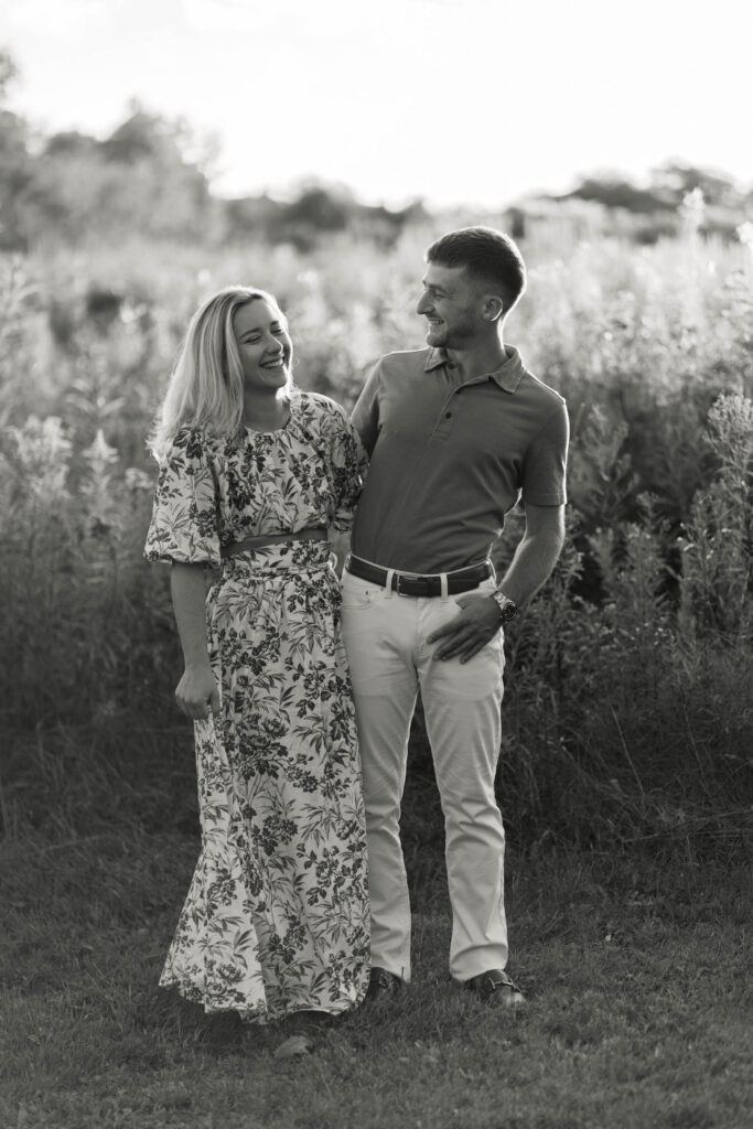 couple stand with sunlit field behind them sugar hill white mountain engagement session