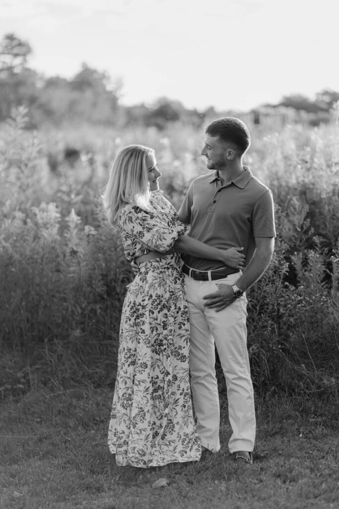couple look at each other with sunlit field behind them