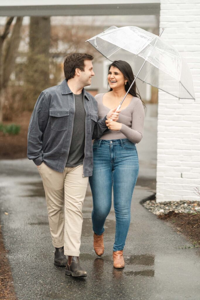 couple walking under umbrella during rain during woodstock vermont engagement session