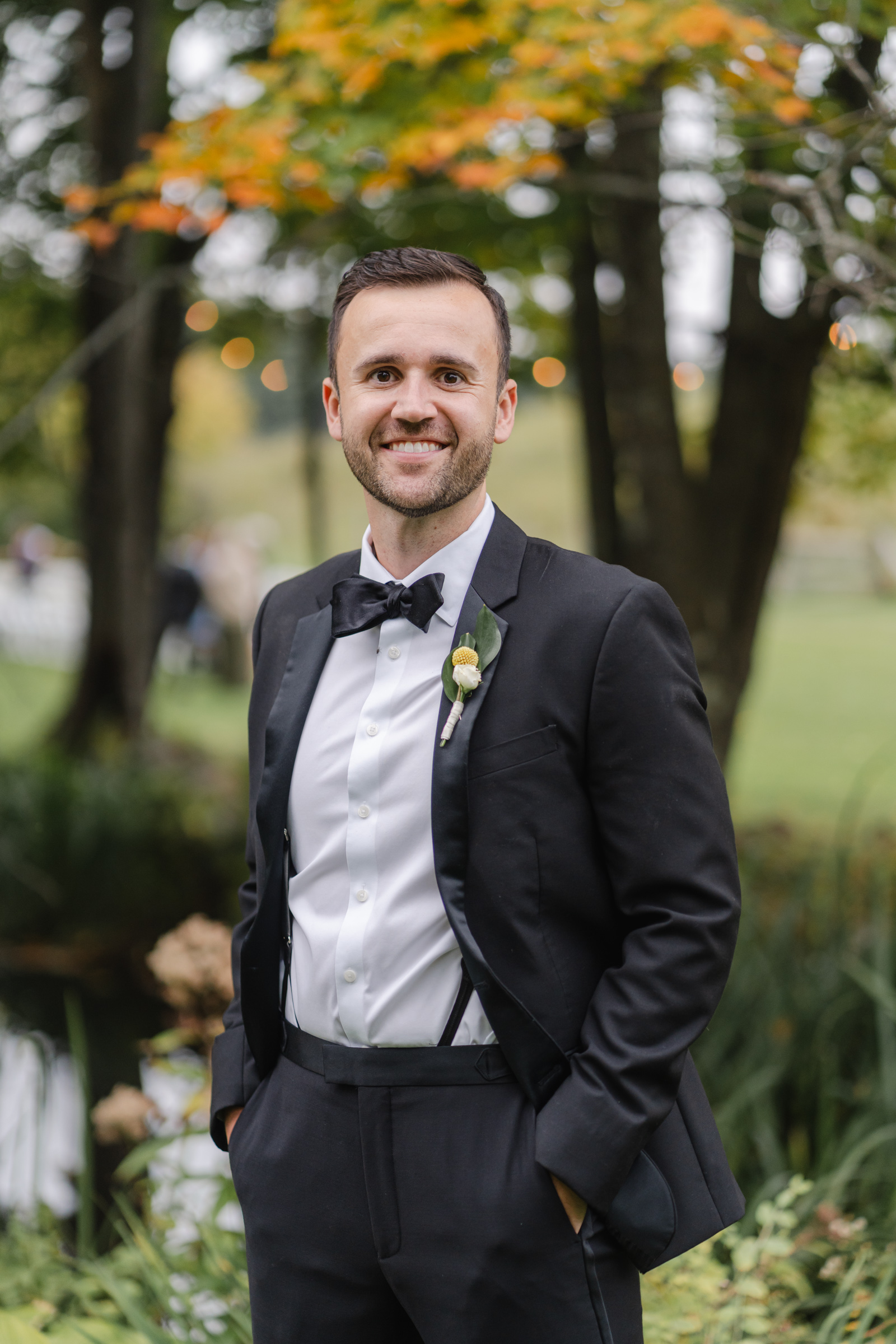 vermont wedding at Inn at round barn portrait of groom with ceremony twinkle lights in background
