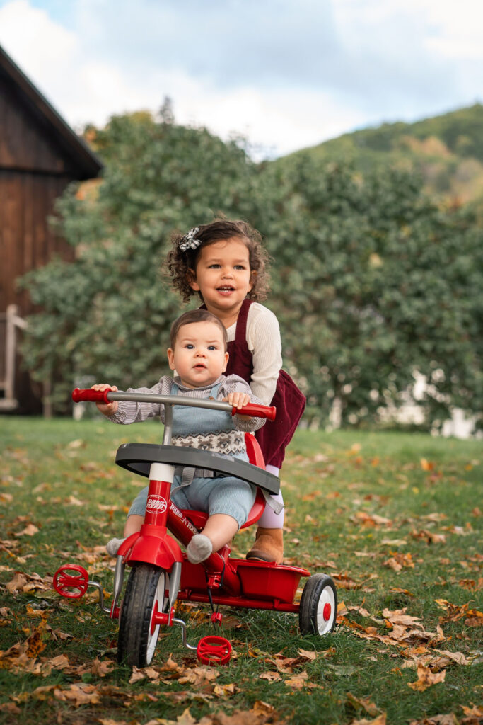 October Family Photos in Woodstock Vermont, kids on tricycle smiling at camera