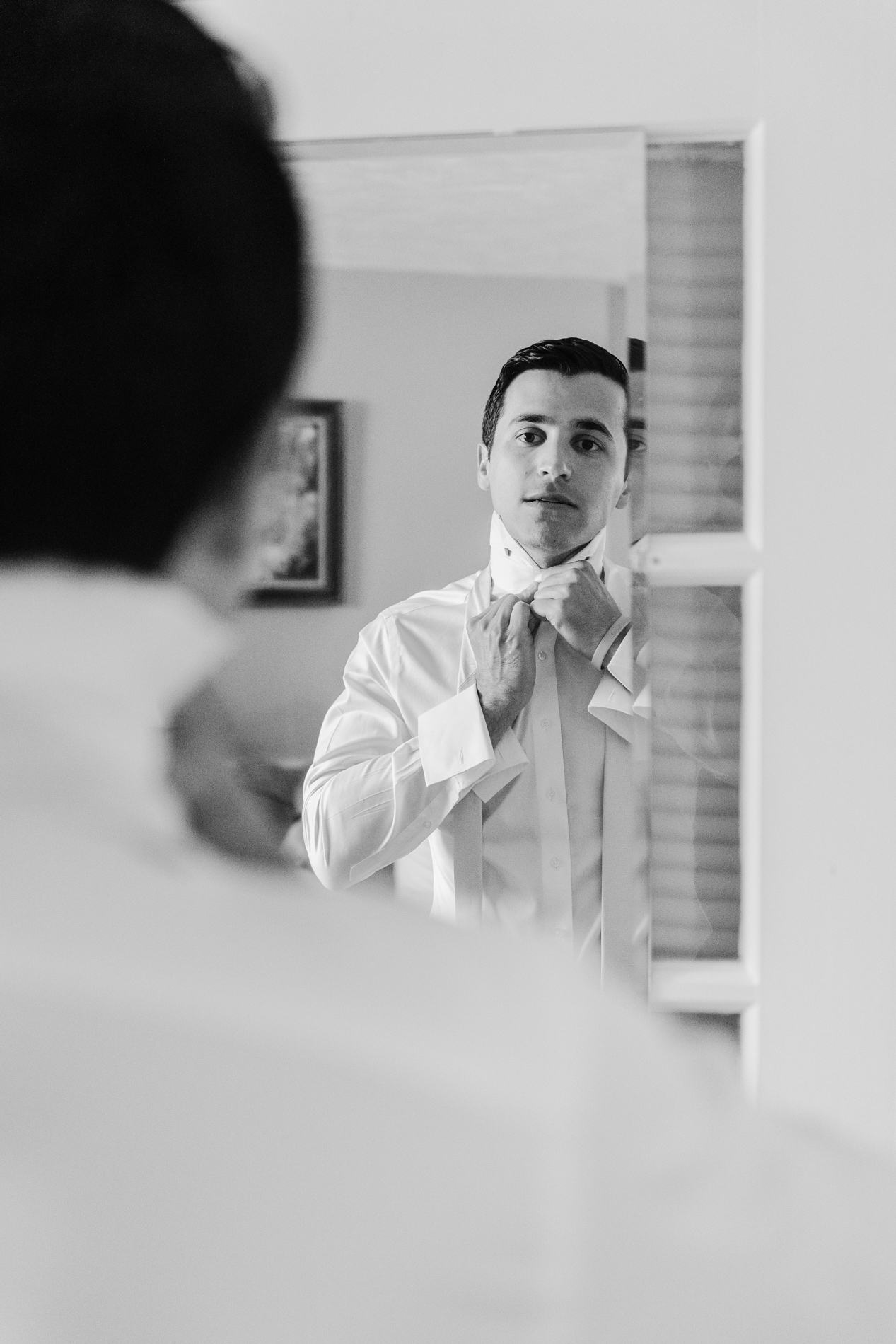 new england wedding photographer - photographing Vermont wedding at Quechee Inn - Groom fixing tie in mirror