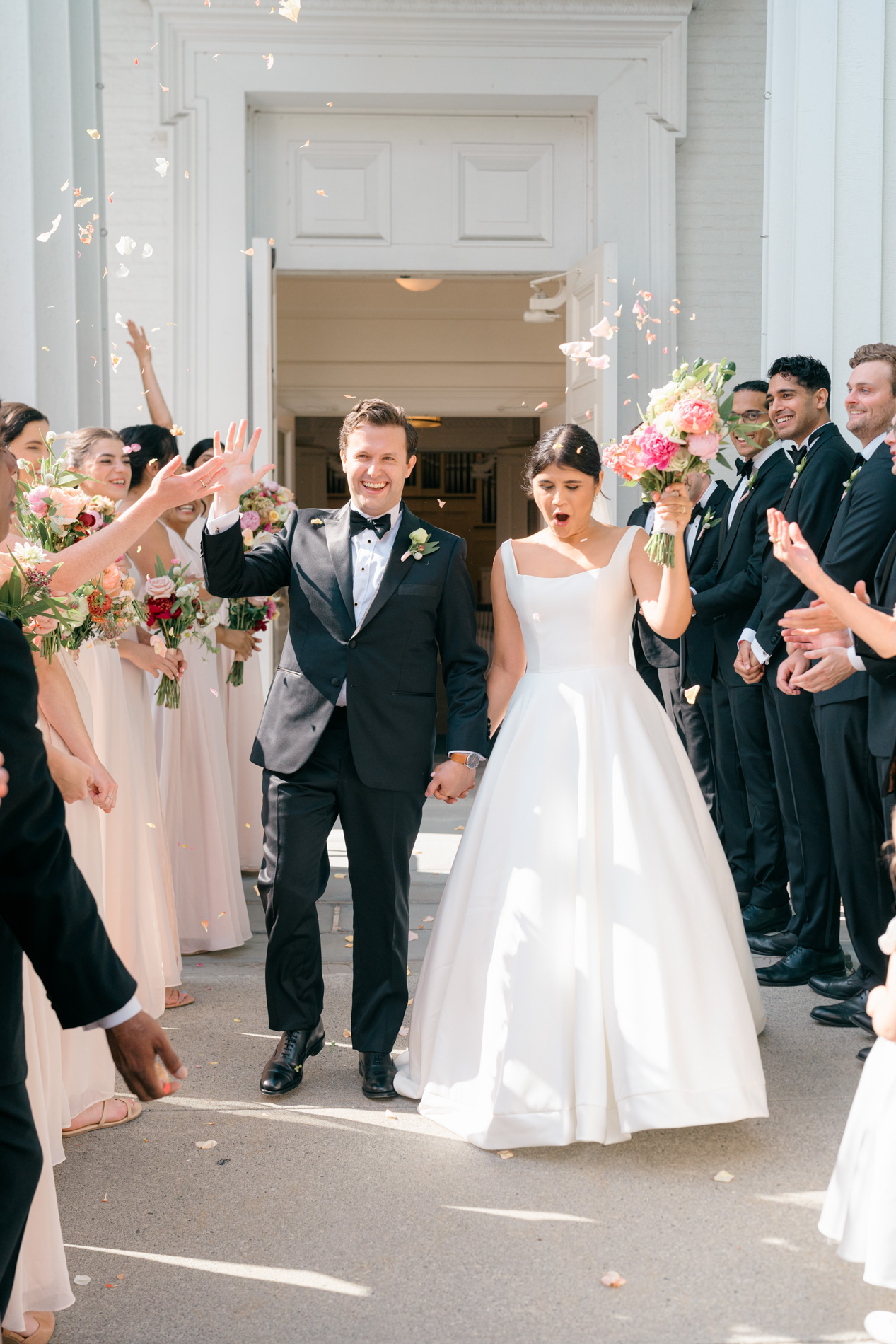 Couple exiting church after ceremony, flowers
