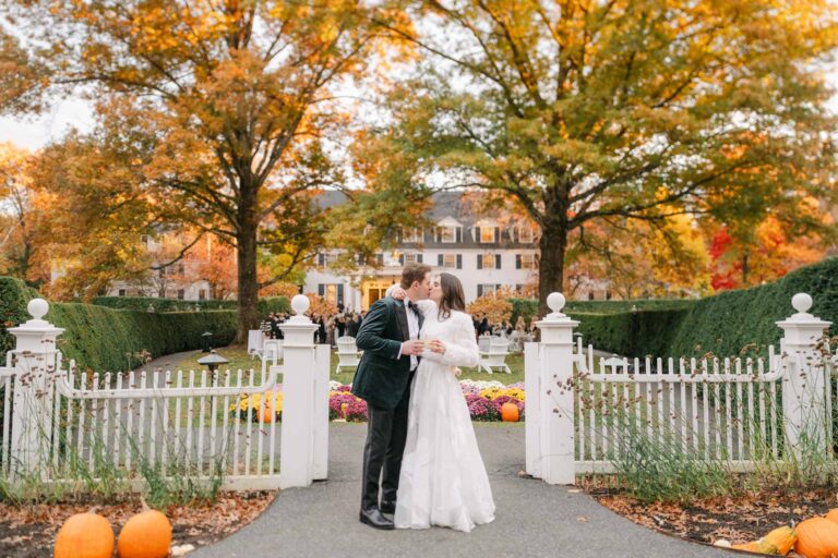 Couple kiss at the front gates of the woodstock inn, vermont wedding