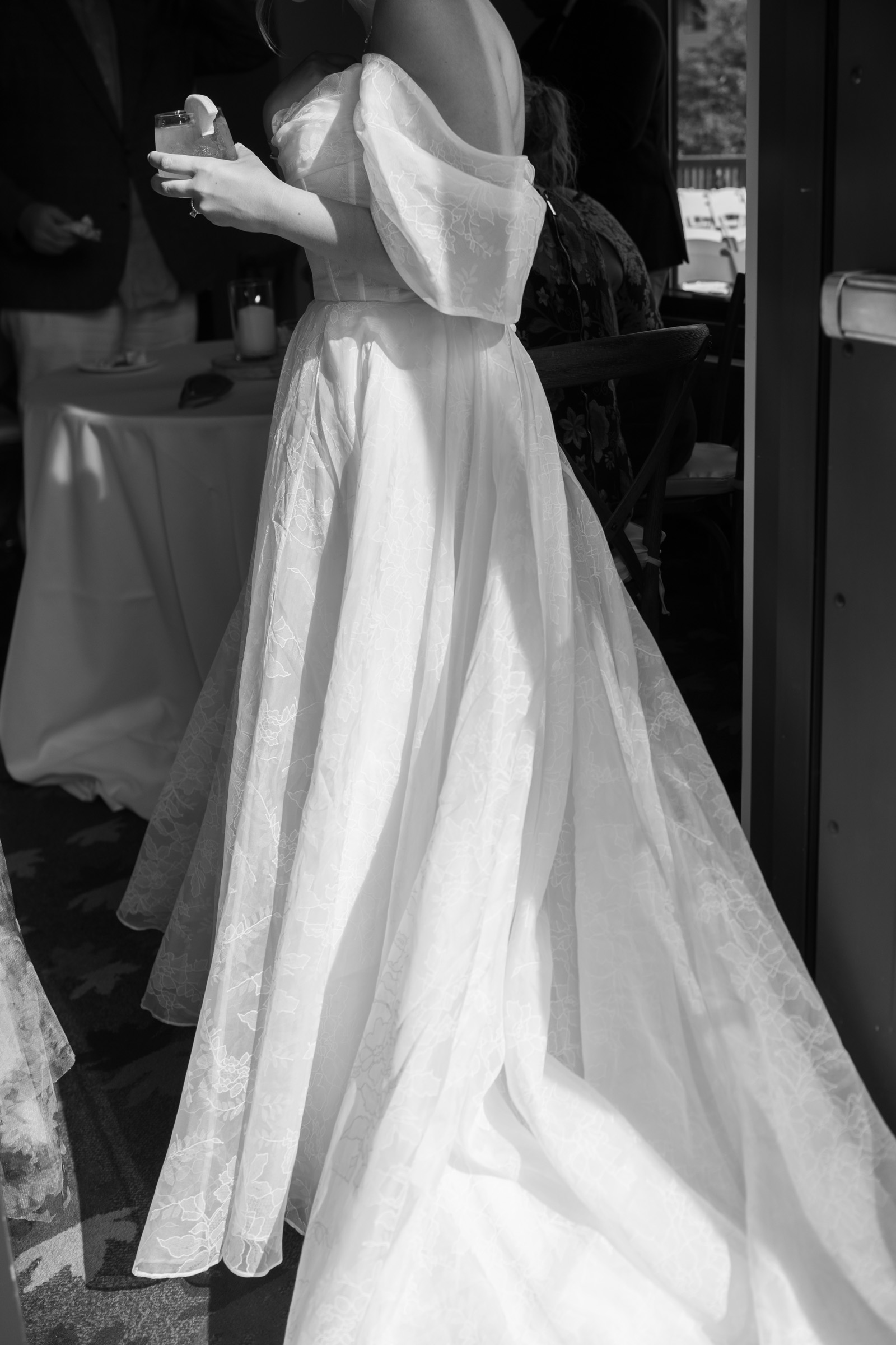Black and white detail of dress, bride standing in doorway