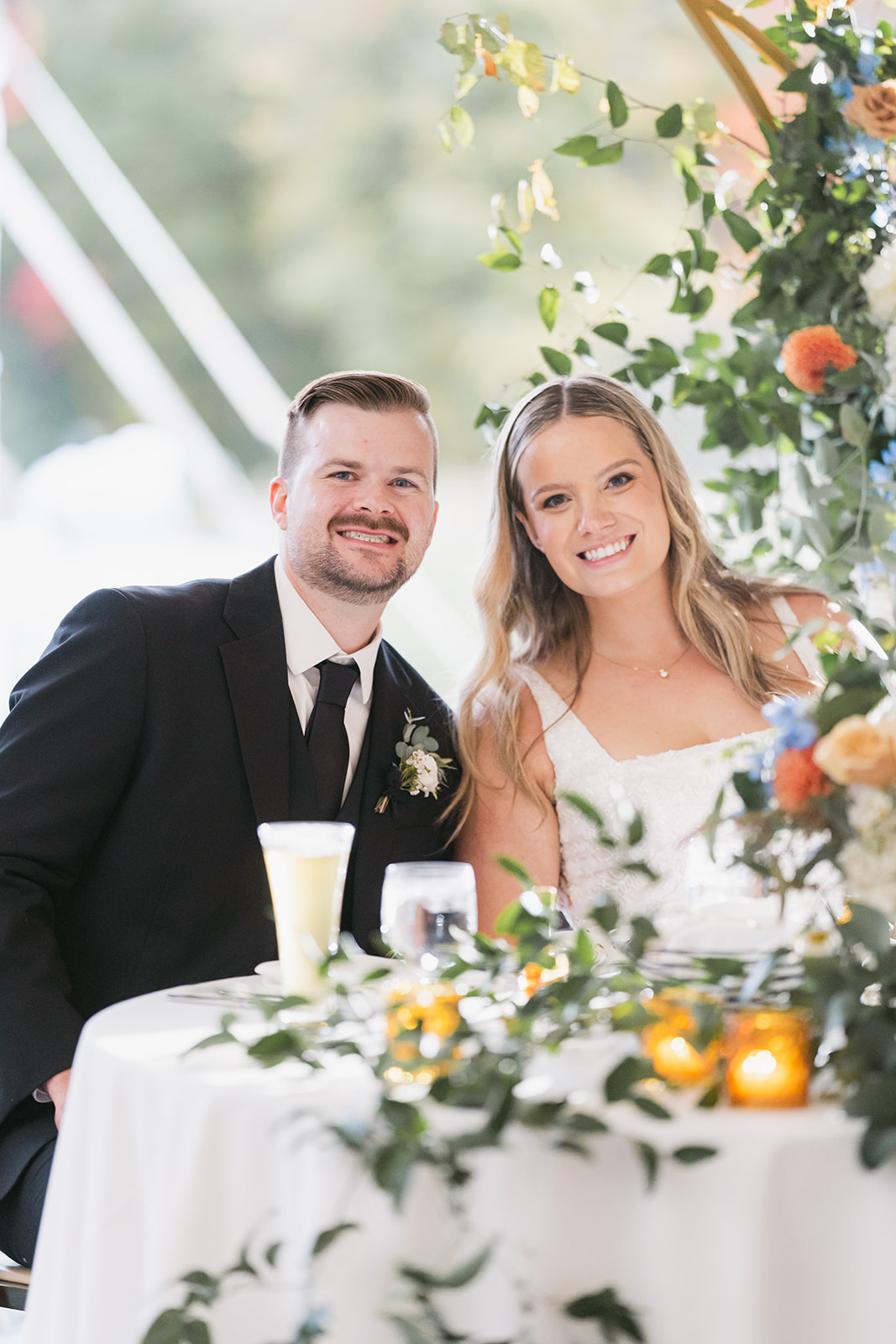 bride and groom sitting at table during wedding in tent