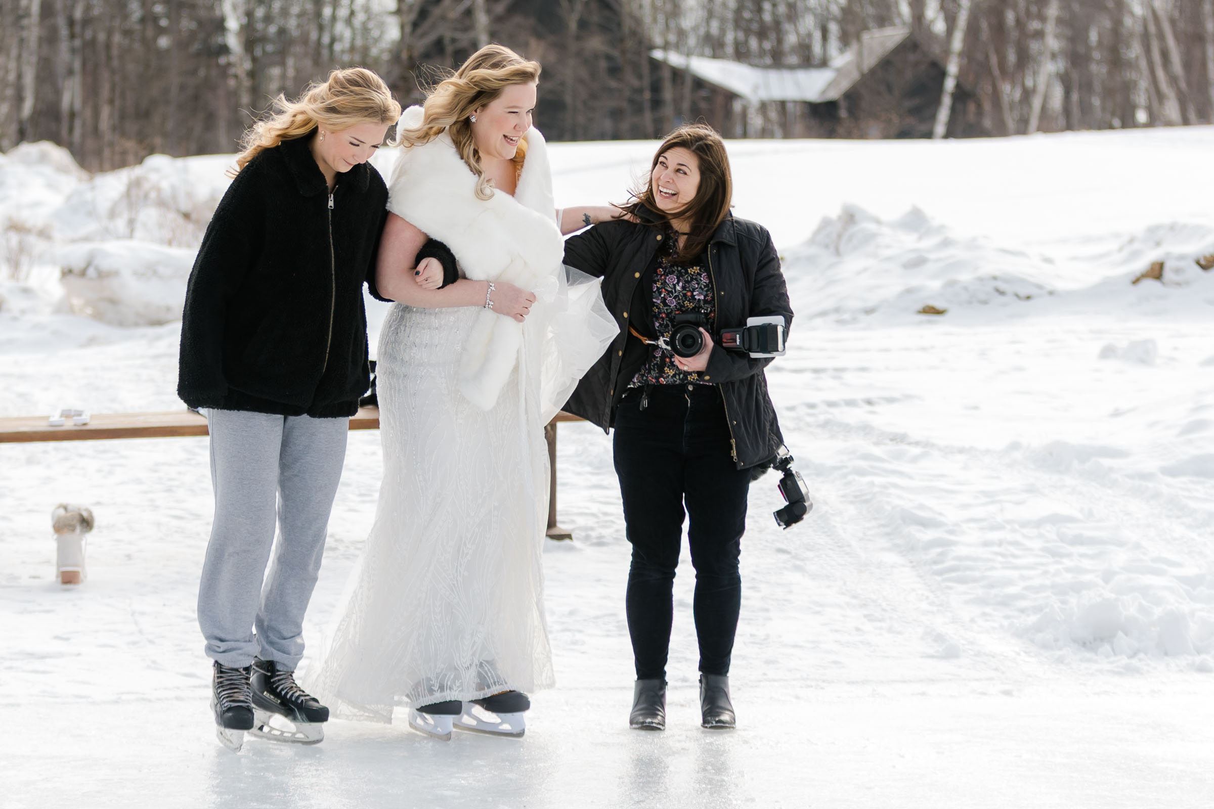 photographer helps bride onto ice during ice skating first look