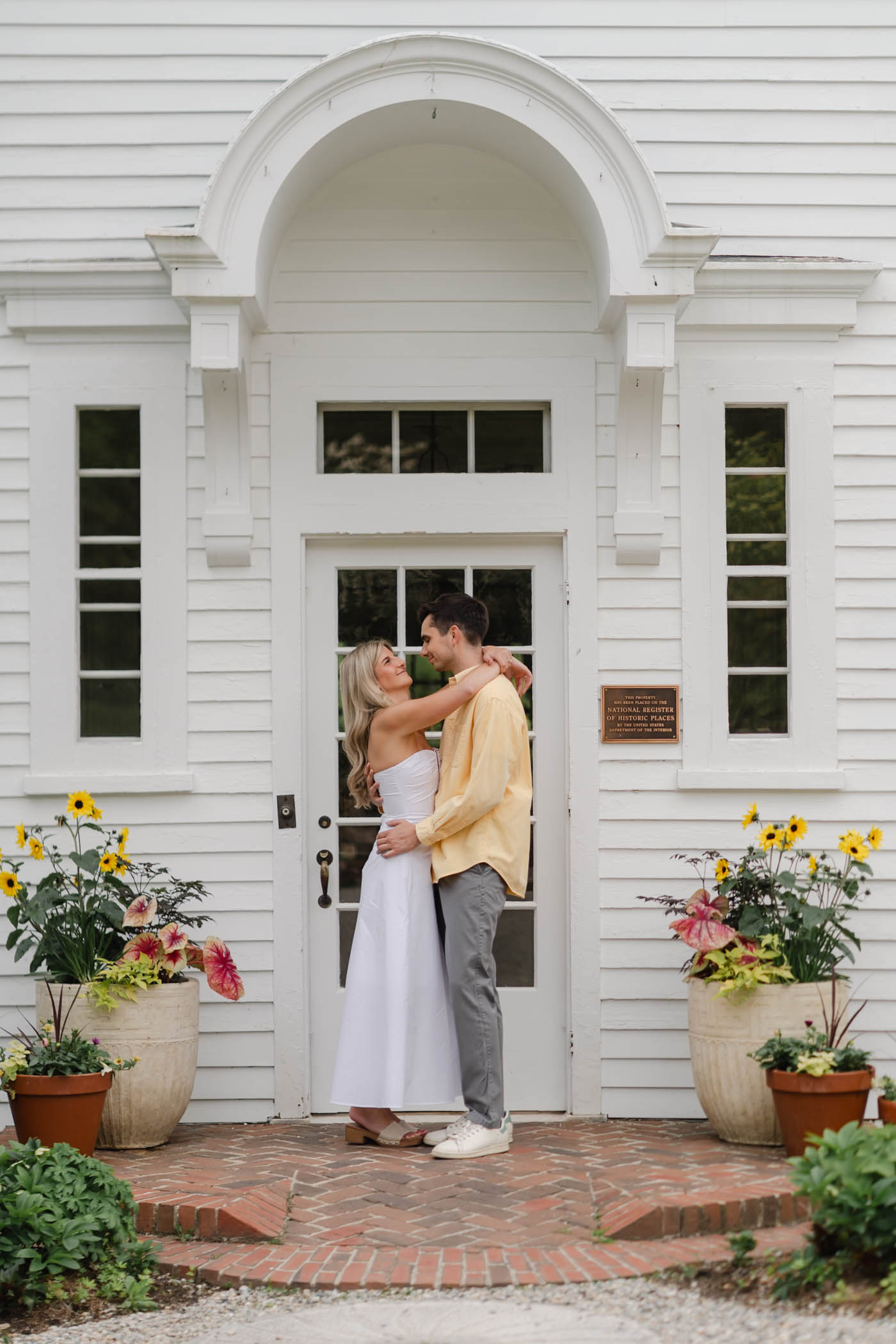 Couple stand under the arch of a doorway during sunapee new hampshire engagement session