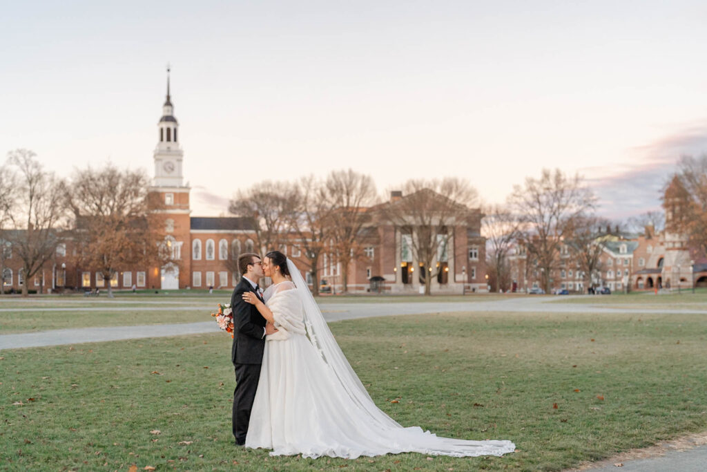 bride and groom on green in Hanover, NH in front of Dartmouth College Baker Library