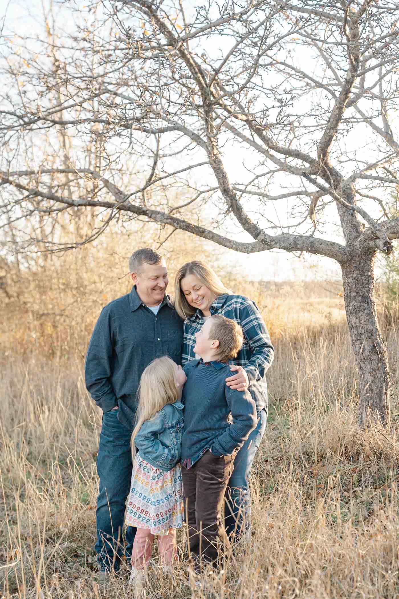 Family standing in a field near a tree with tall golden grass around them