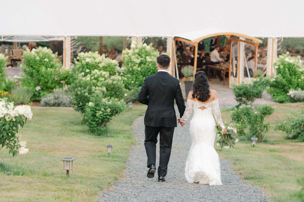 Couple walking to reception tent during wedding at the preserve at chocorua