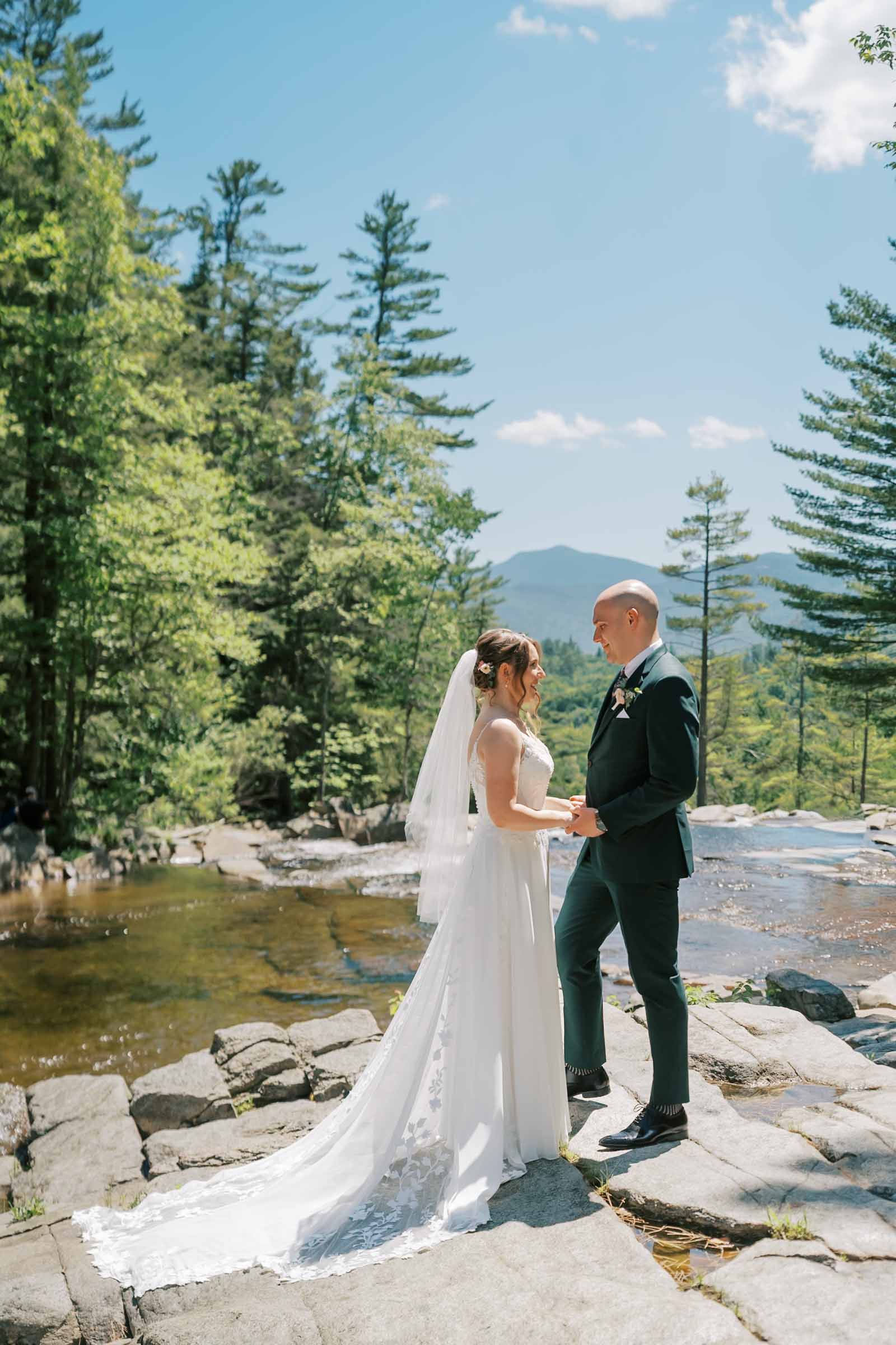 Wedding at Eagle Mountain House in the white mountains, couple stand on rocks at Jackson Falls, during first look